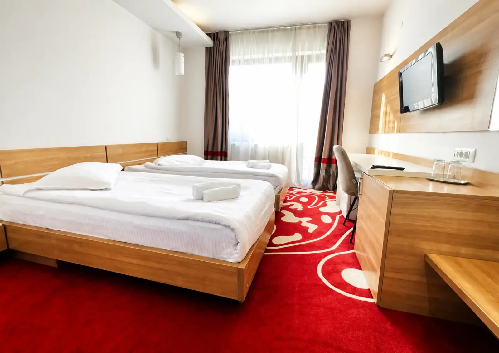 Twin room at Hotel Ave Lux with two beds, a desk and a balcony door