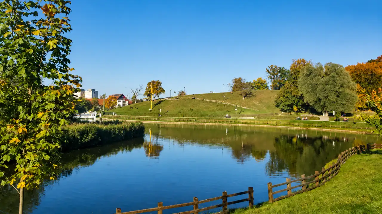 Lake Noua near Hotel Ave Lux, with tree-lined shores and a grassy hill beyond