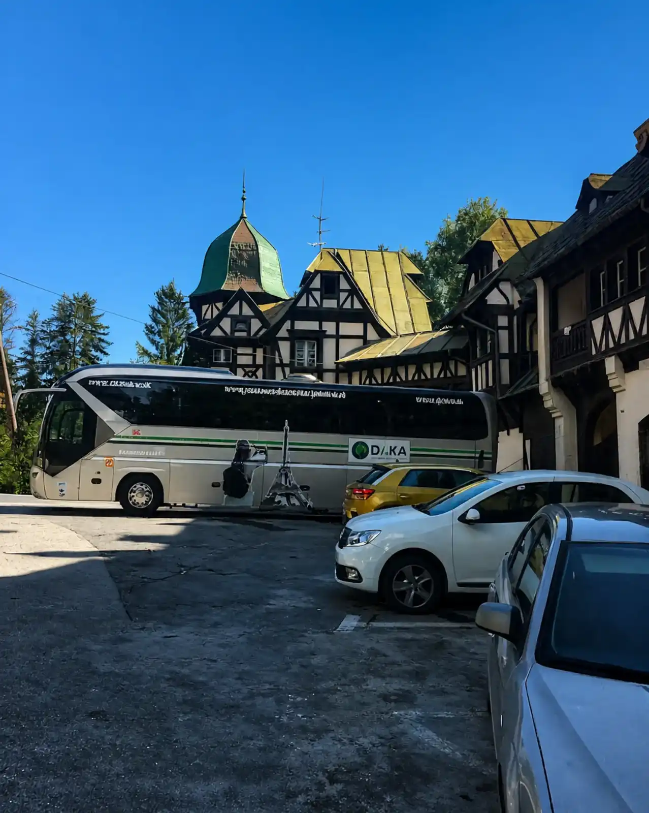 Cars and a coach parked on the paved parking area beside the hotel