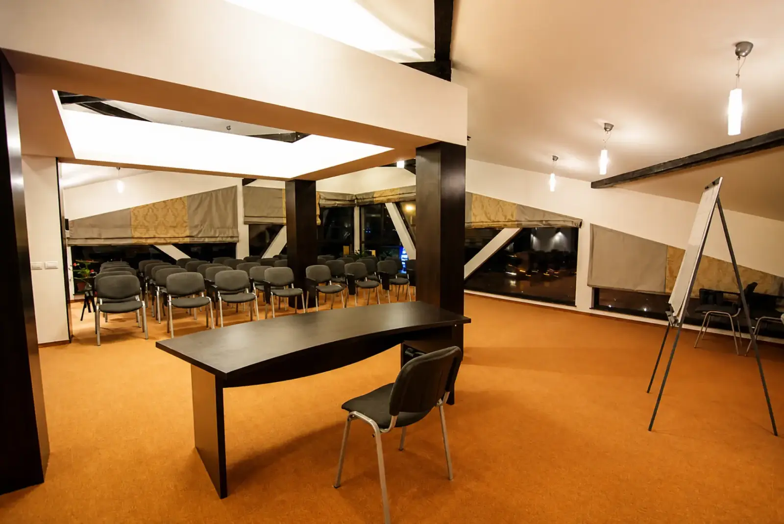 Meeting room at Hotel Ave Lux set with rows of chairs, a presenter desk and a flip chart